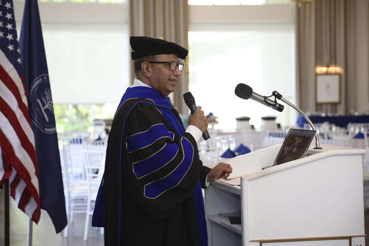 An Aleph University faculty member delivering an address at the podium during the 2026 commencement ceremony.