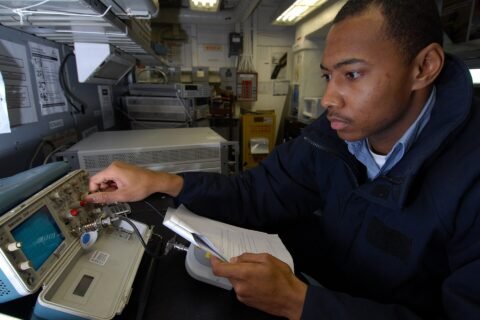 A technician calibrating an oscilloscope in a testing and calibration laboratory, illustrating medical device safety and performance testing.