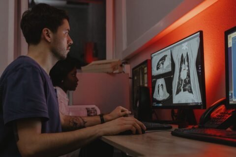 Two specialists reviewing chest scans on radiology monitors