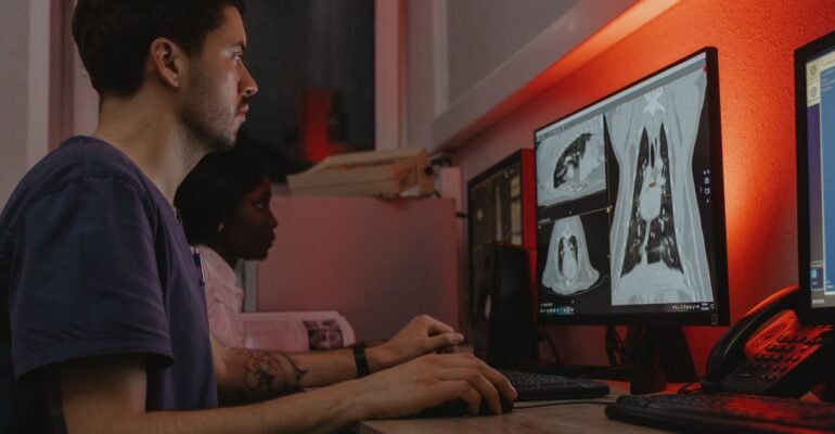 Two specialists reviewing chest scans on radiology monitors