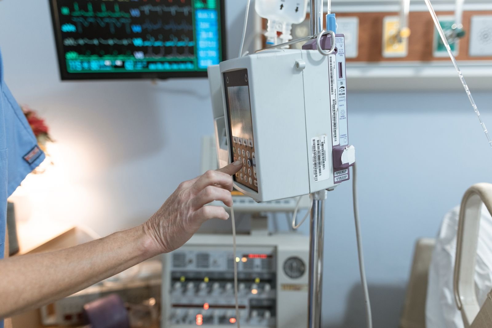 Gloved hands adjusting a medical device at a patient bedside