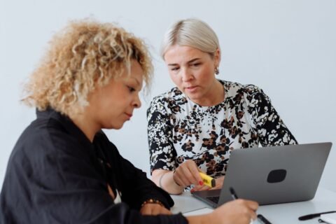 Two colleagues reviewing work together on a laptop