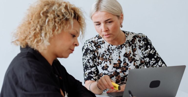 Two colleagues reviewing work together on a laptop